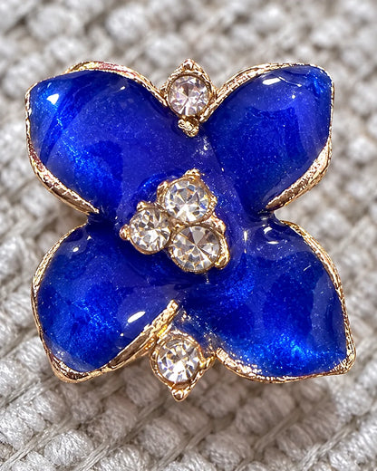 Close-up of a blue camellia stud on grey knit with crystal centre