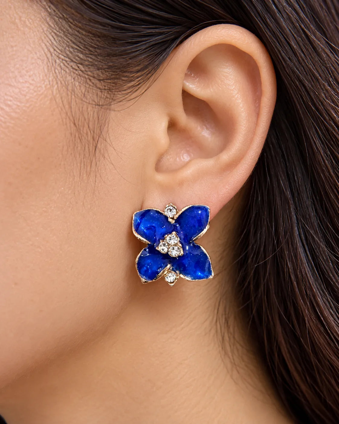 Close-up of the cobalt blue camellia flower stud worn on the ear