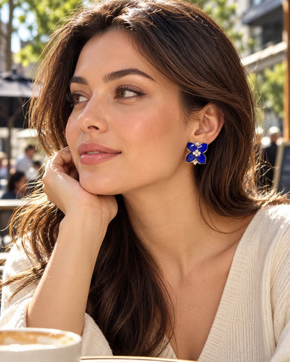 Model at a café in a cream knit wearing the blue camellia studs