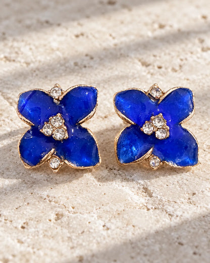 Blue enamel camellia flower studs resting on stone