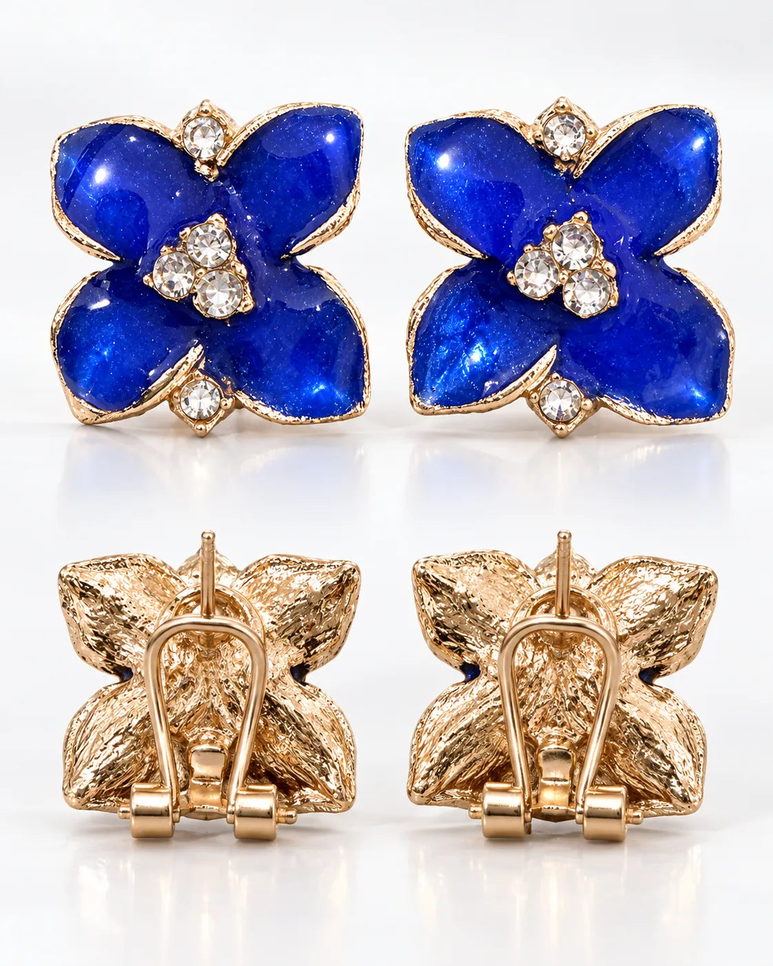 Fronts and gold-tone backs of the blue camellia studs on white
