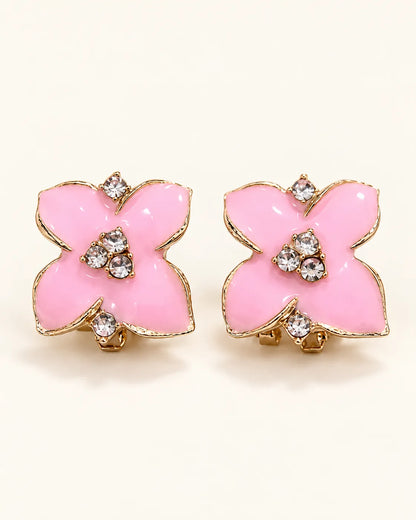 Pair of candy-pink enamel camellia flower stud earrings on cream