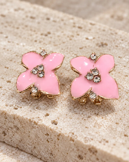 Pink enamel camellia flower studs resting on stone