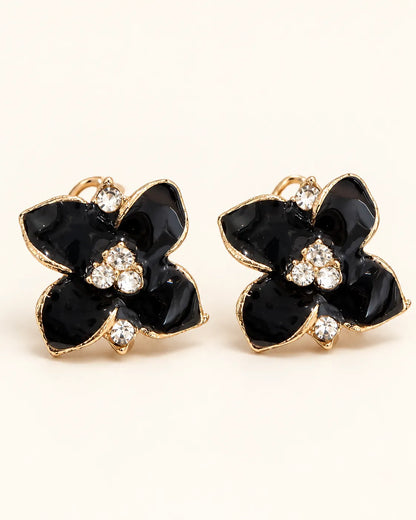 Pair of black enamel camellia flower stud earrings with crystal centres on cream
