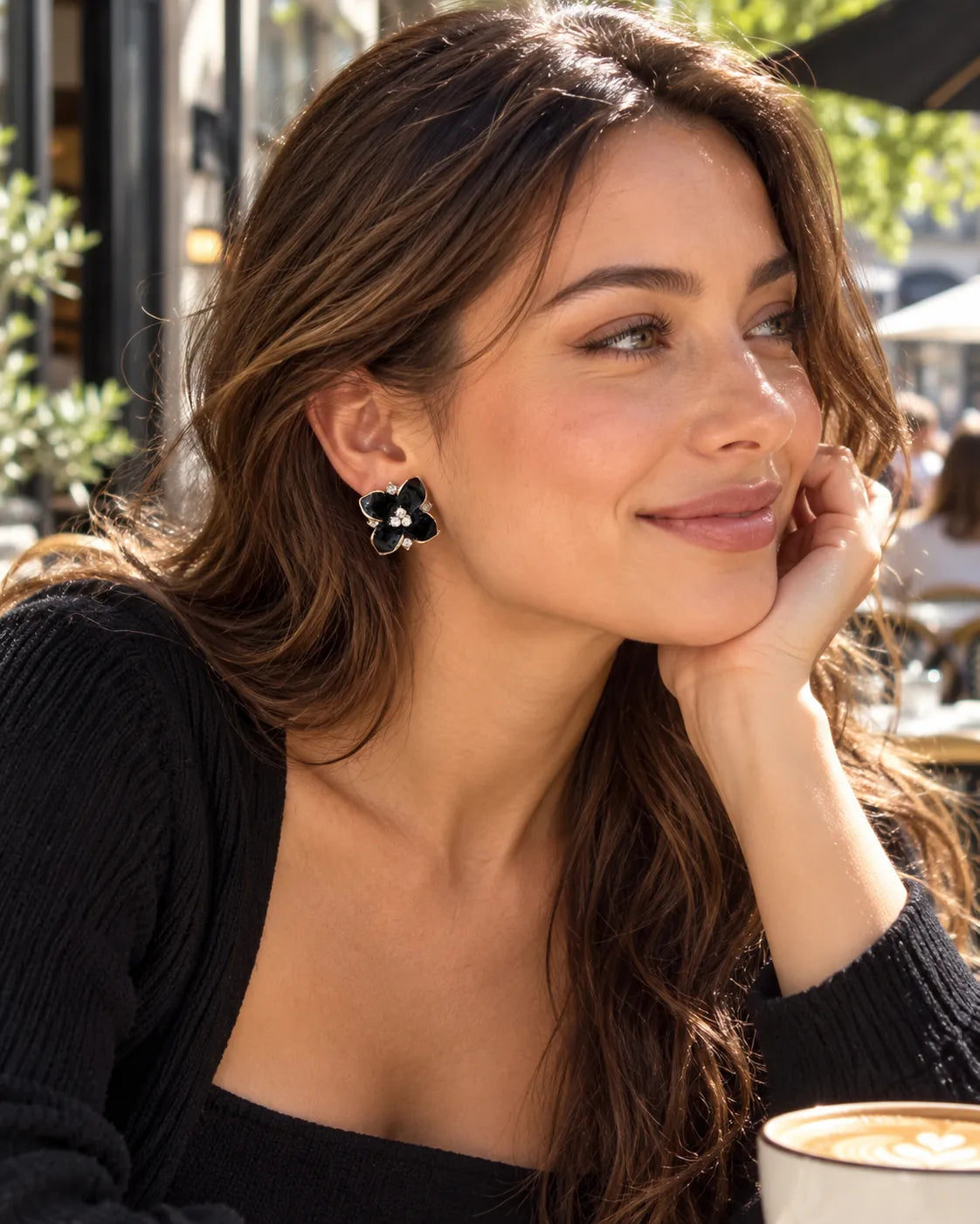 Model at a café in a black top wearing the black camellia studs