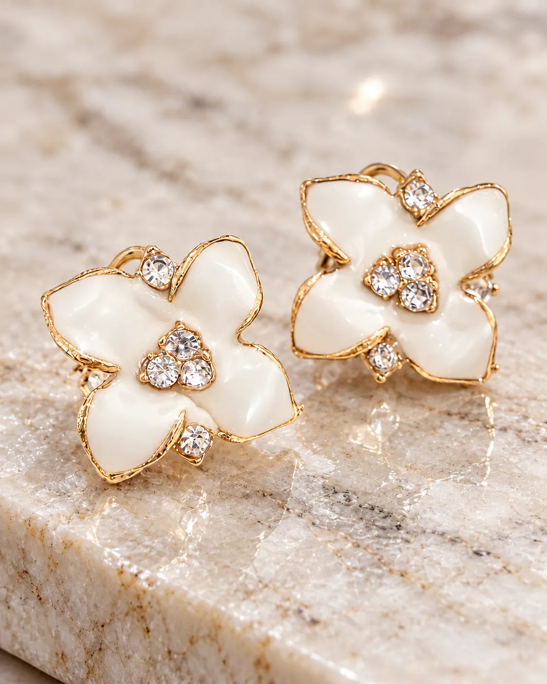White enamel camellia flower studs resting on marble