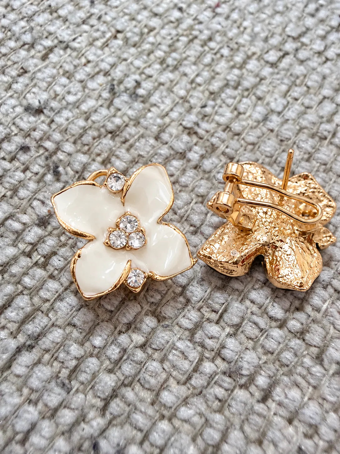 White camellia flower stud and gold-tone back resting on grey knit