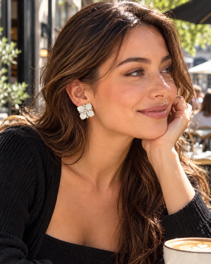 Smiling model at a café in a black top wearing the white camellia studs