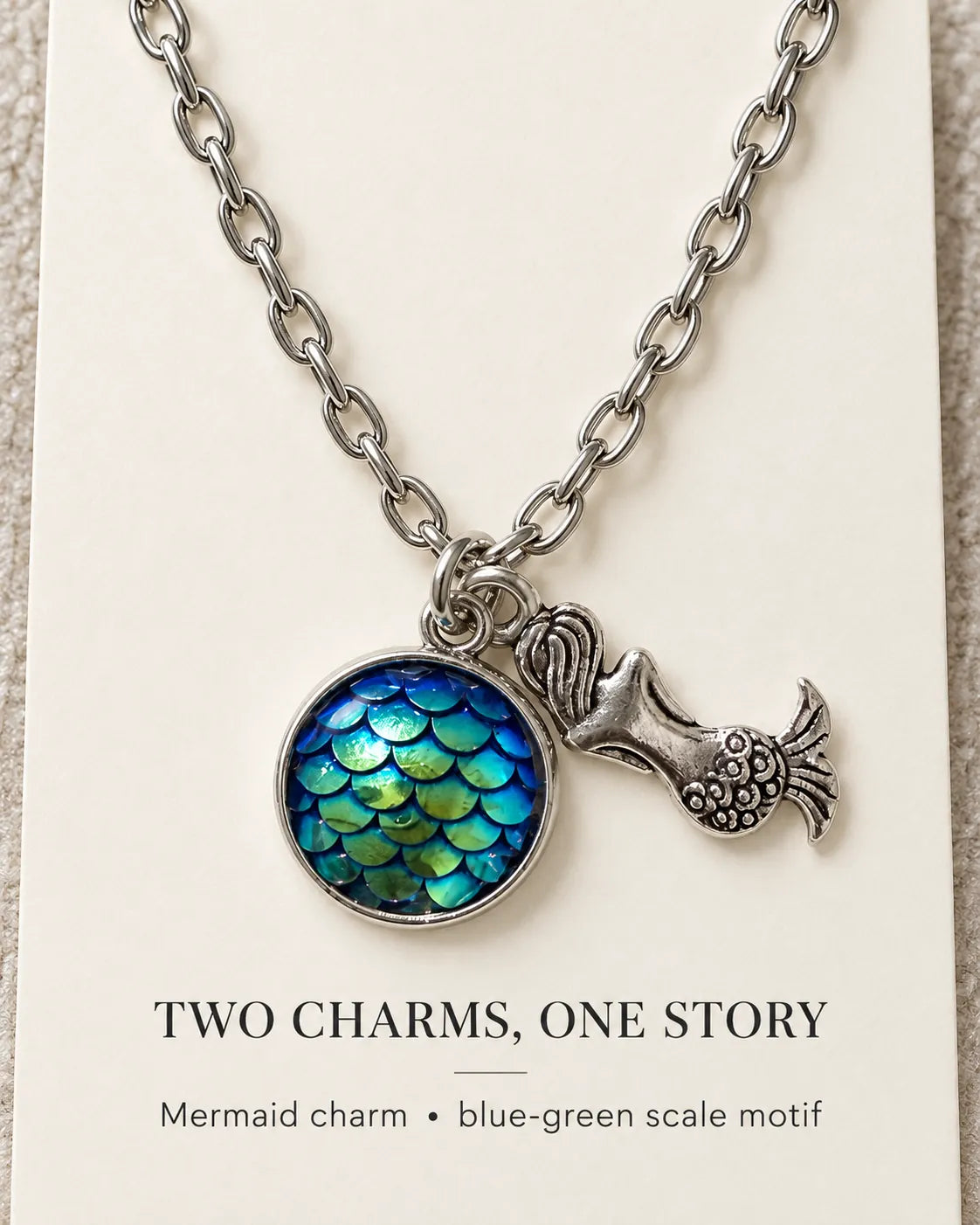 Mermaid scale necklace on a card with Two Charms, One Story text