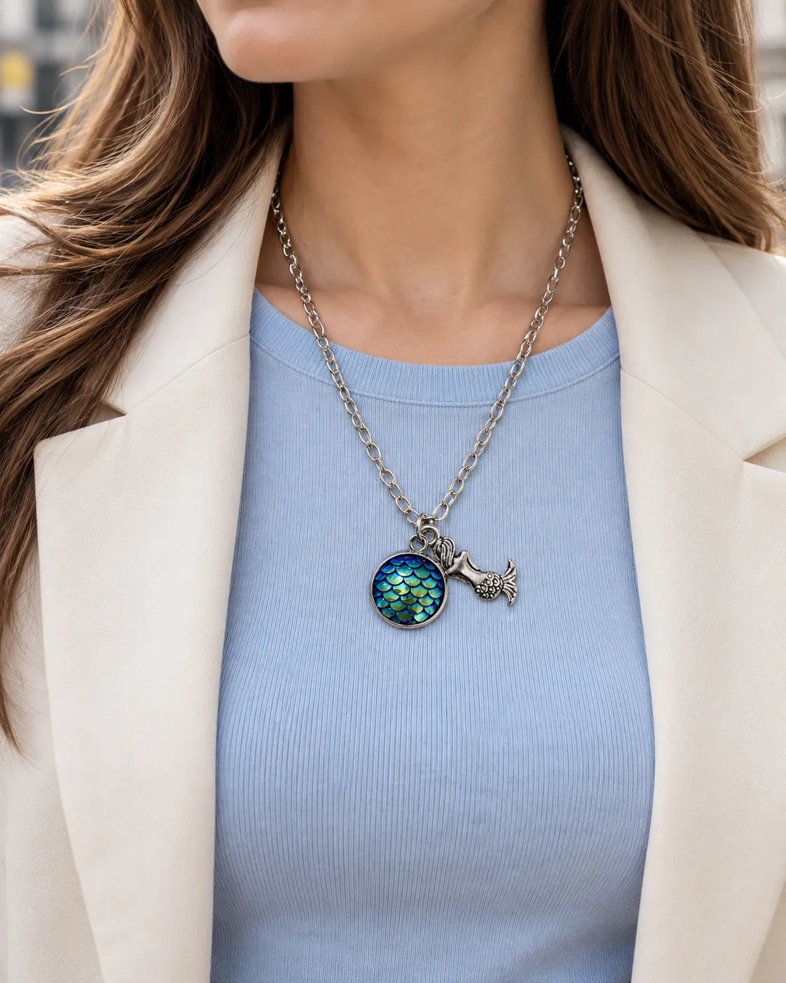 Model in a light blue top and cream blazer wearing the mermaid pendant