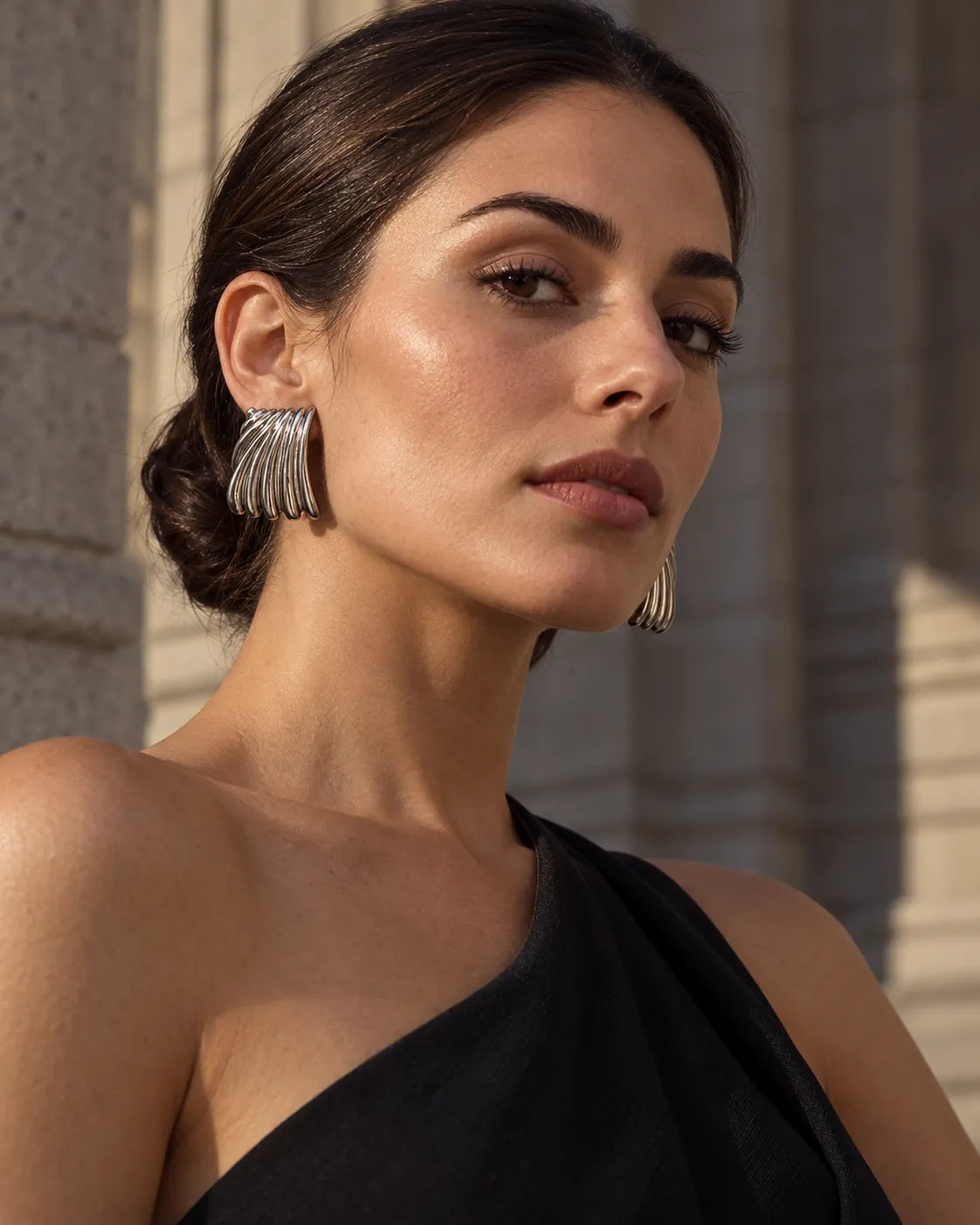 Model in a black one-shoulder top wearing the silver ribbed studs