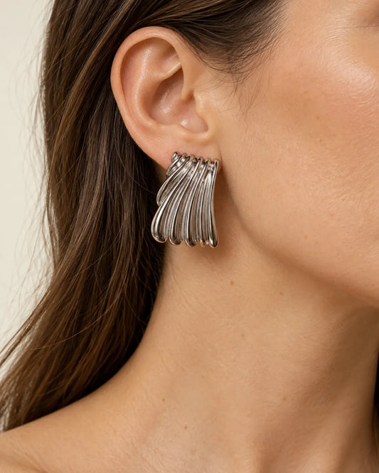 Close-up of a silver ribbed statement stud worn on the ear