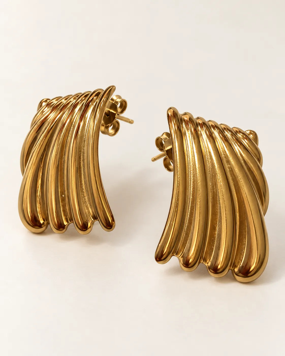 Angled view of the gold striped ribbed statement studs