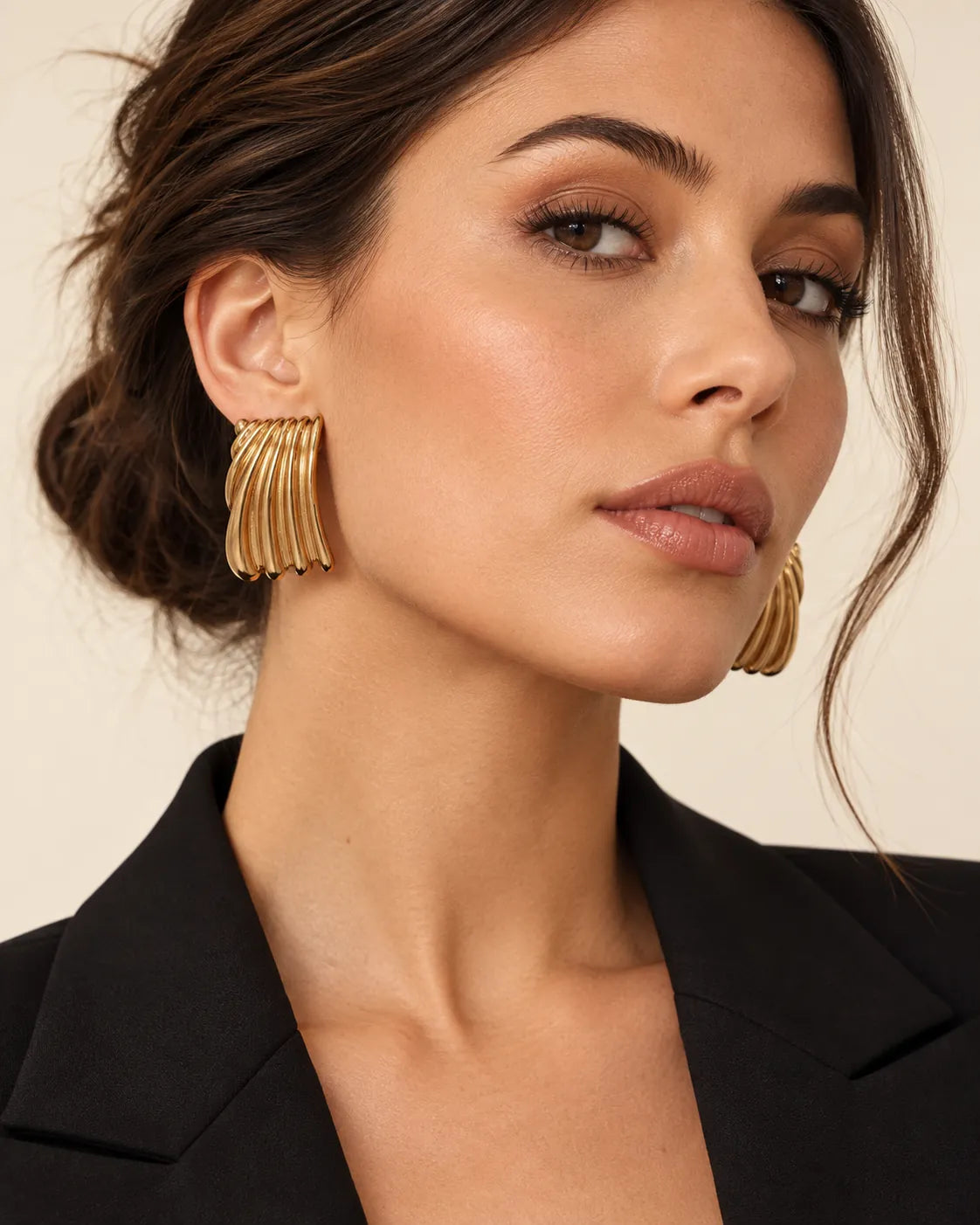 Model in a black blazer wearing the gold ribbed stud earrings