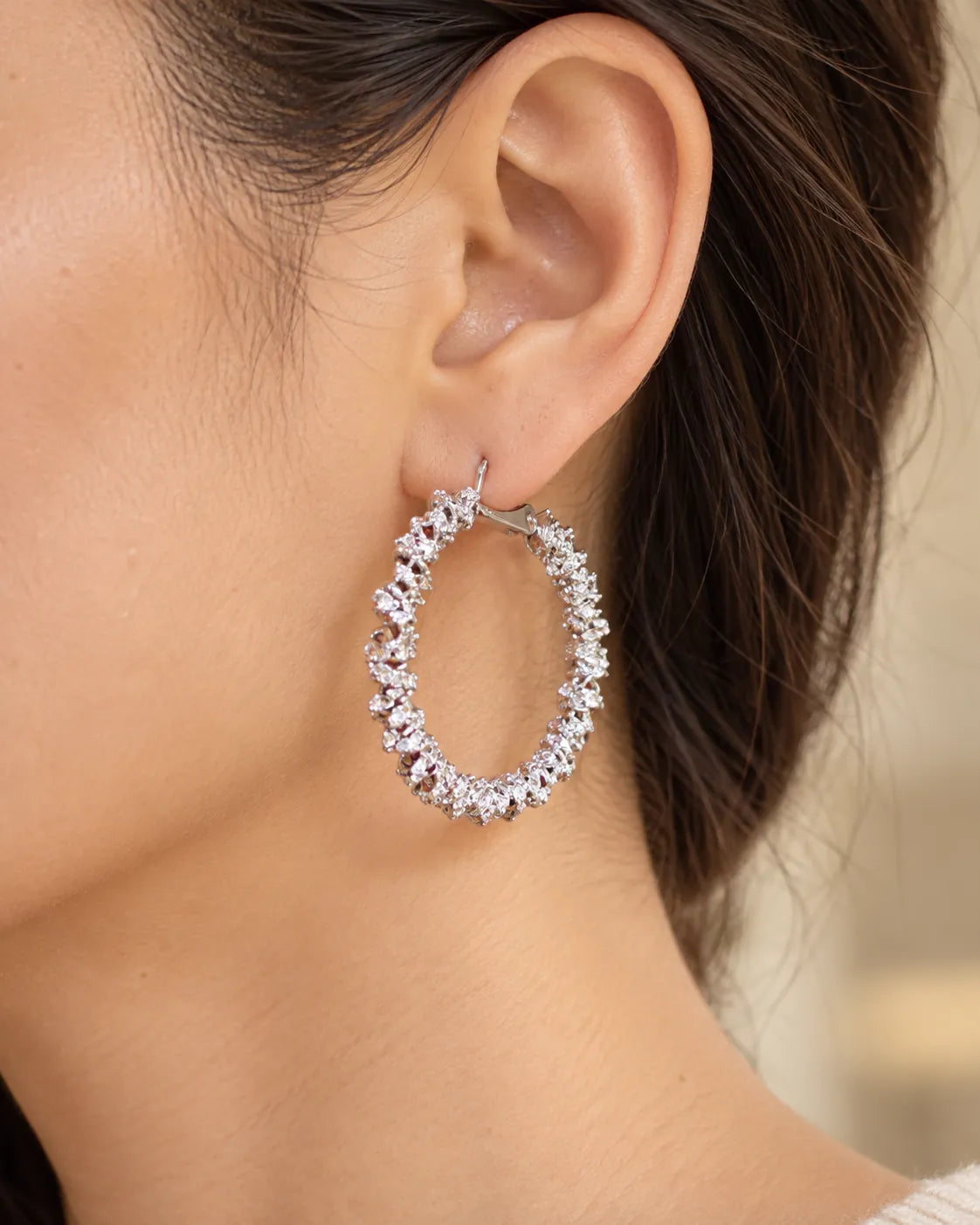 Close-up of a silver crystal cluster hoop worn on the ear