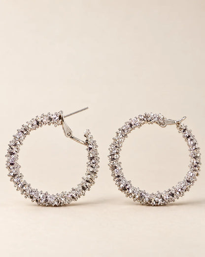 Silver crystal cluster hoops laid side by side on cream