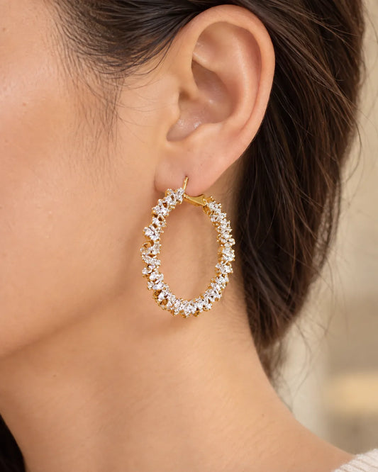 Close-up of a gold crystal cluster hoop worn on the ear