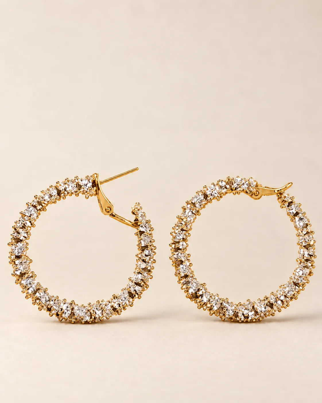 Gold crystal cluster hoops laid side by side on cream