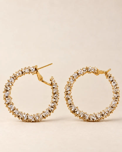 Gold crystal cluster hoops laid side by side on cream