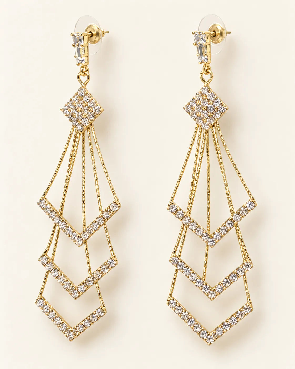 Pair of long gold chevron tassel drop earrings with crystals on cream