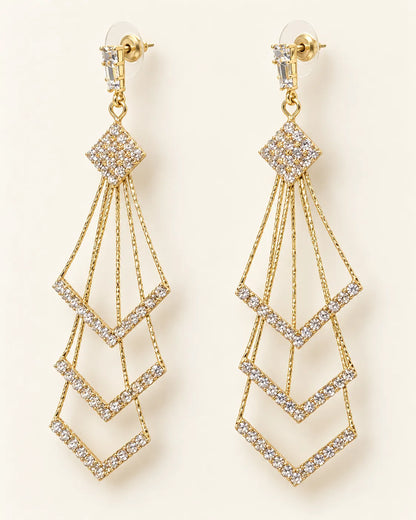 Pair of long gold chevron tassel drop earrings with crystals on cream