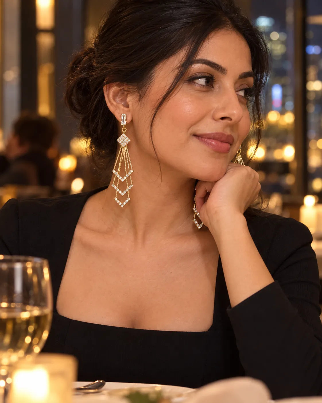 Model at an evening dinner wearing the long gold chevron drop earrings