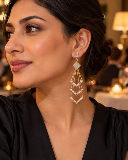 Model in a black top wearing the gold crystal chevron tassel earrings