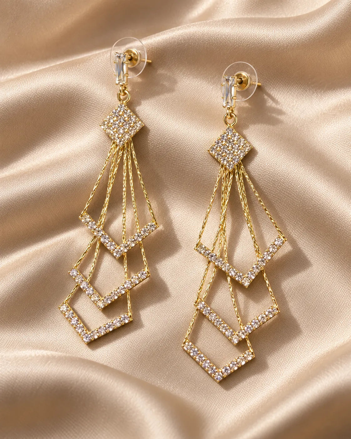 Gold chevron tassel drop earrings laid on champagne satin