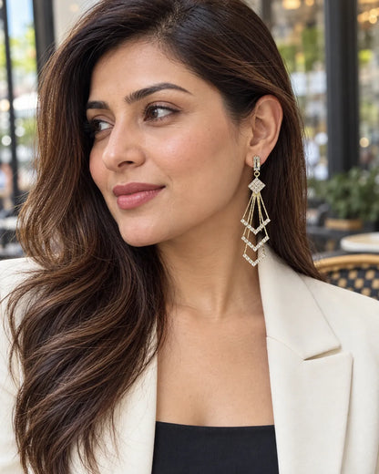 Model in a cream blazer wearing the long gold chevron tassel earrings