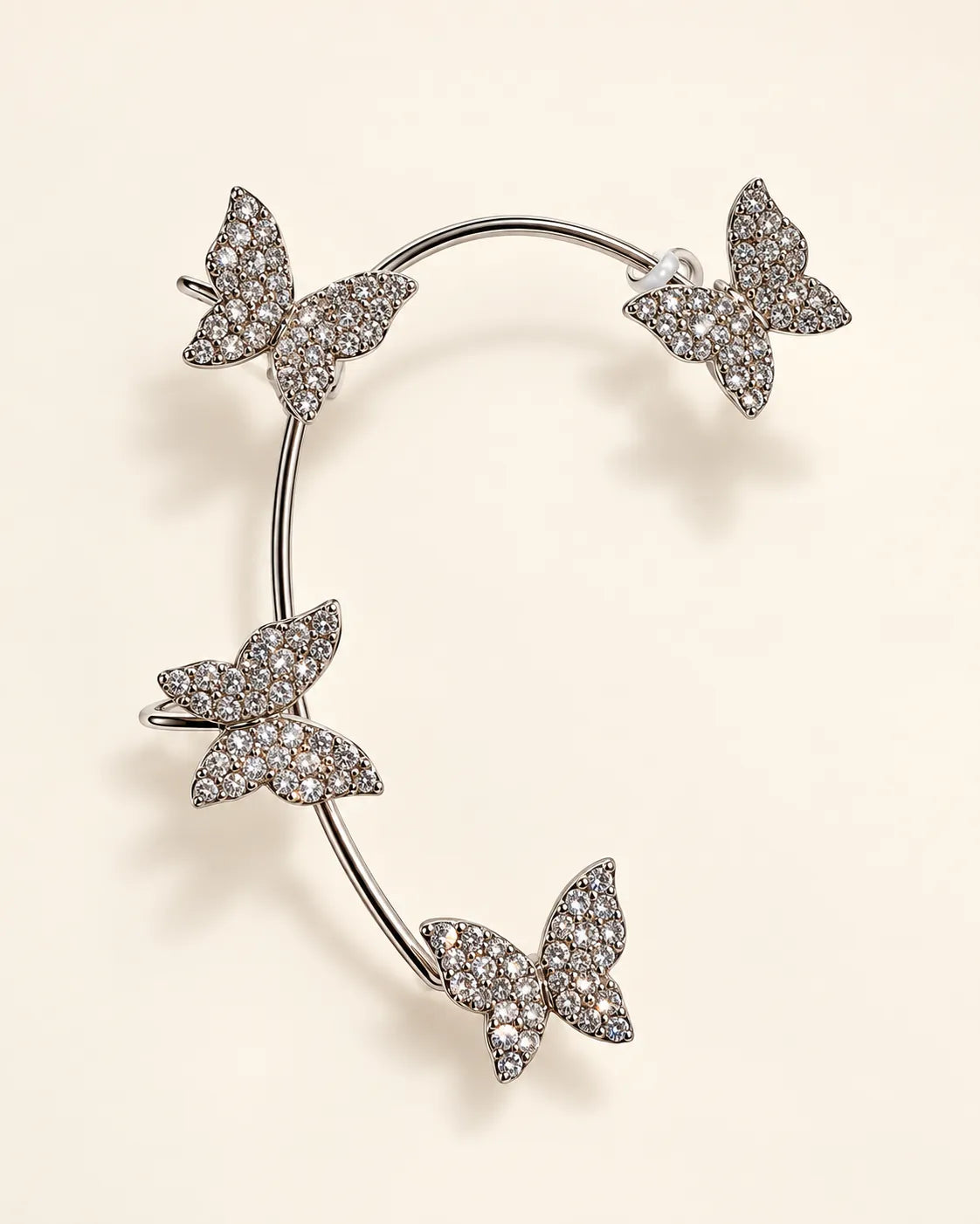 Silver curved ear cuff with four pavé crystal butterflies on cream