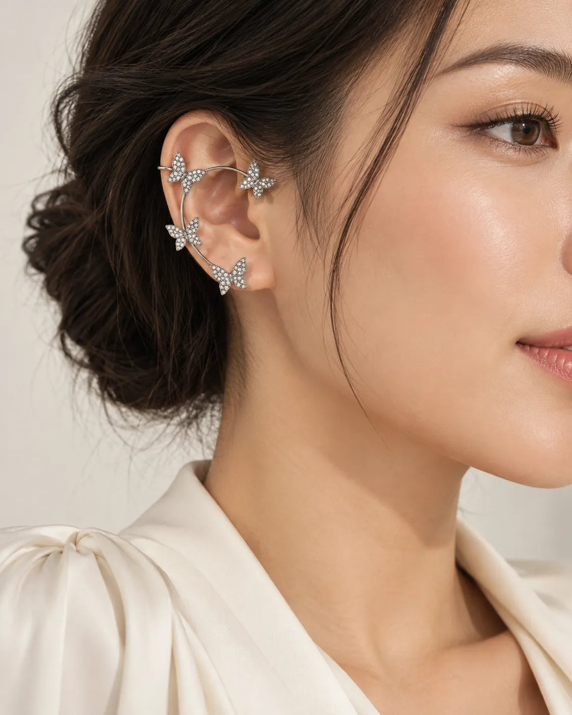 Profile of a model with hair up wearing the silver butterfly ear cuff
