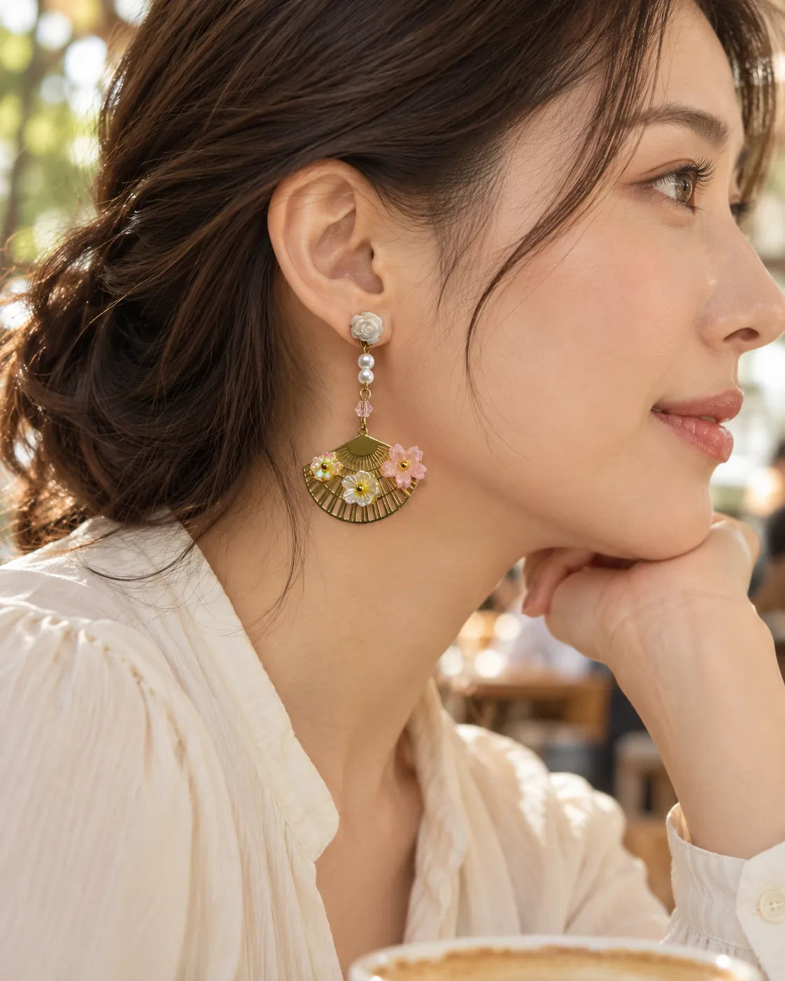 Side profile of a model wearing the gold fan and flower dangle earring