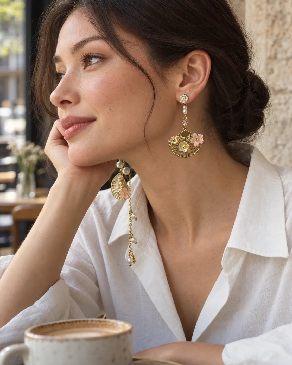 Model in a white shirt at a cafe wearing the gold fan dangle earring