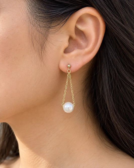 Close-up of a model's ear wearing the gold pearl chain drop earring