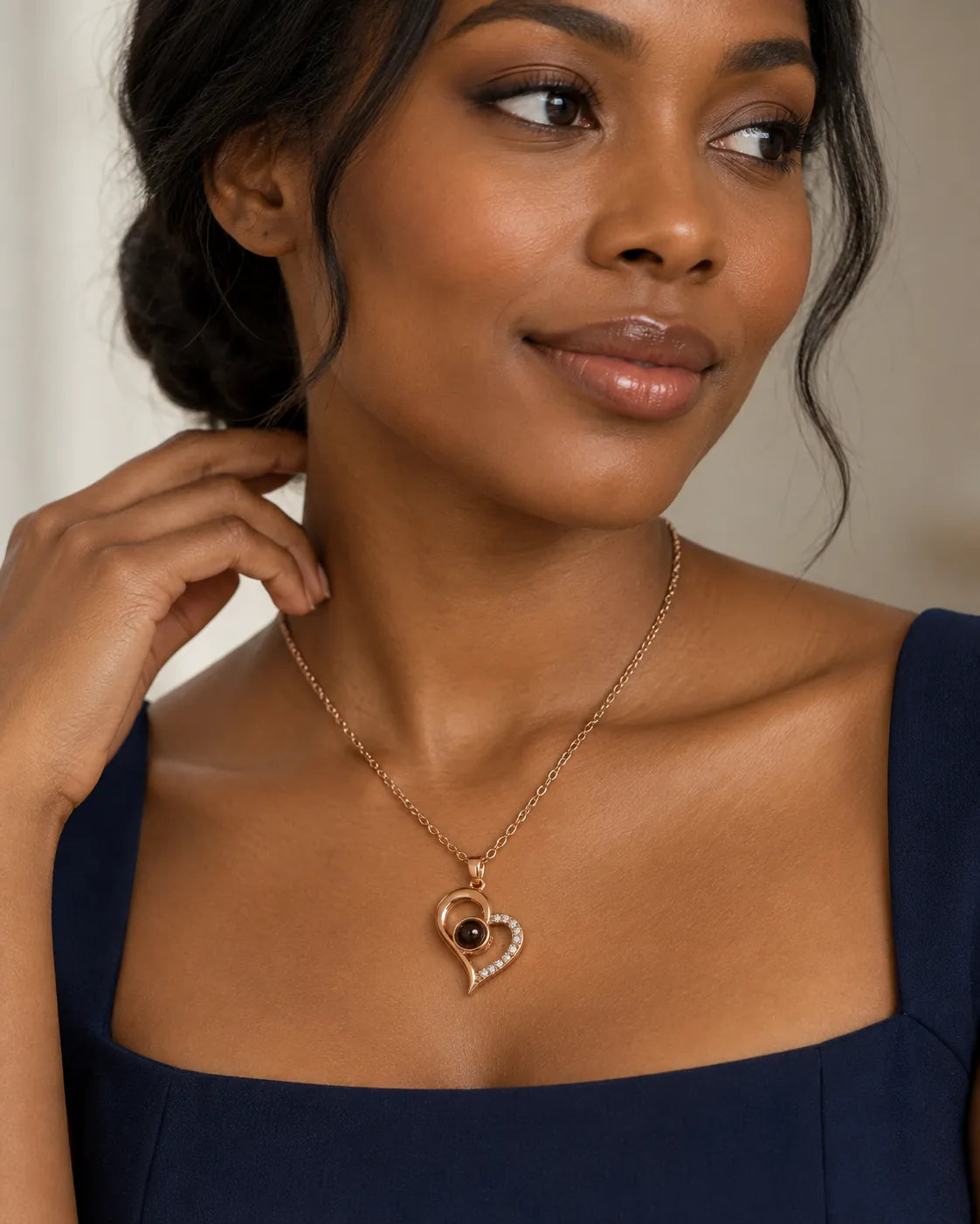 Model in a navy top wearing the rose gold projection heart necklace