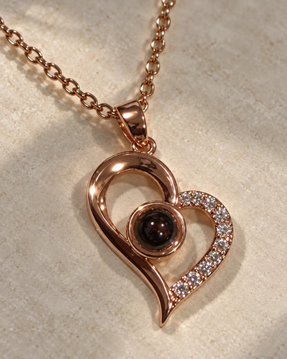 Rose-gold-tone projection heart pendant resting on textured linen