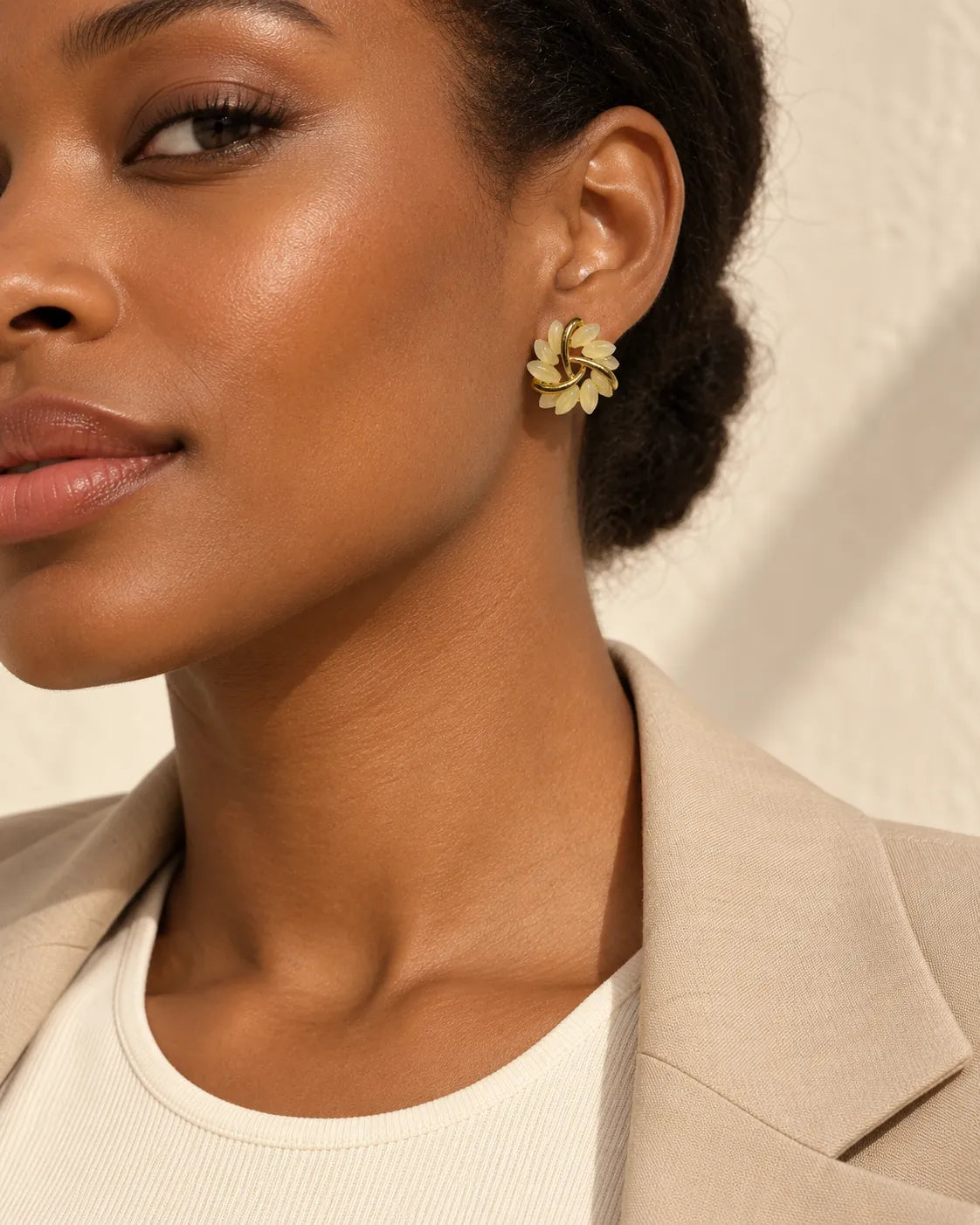 Close crop of a model in a beige blazer wearing the opal flower stud