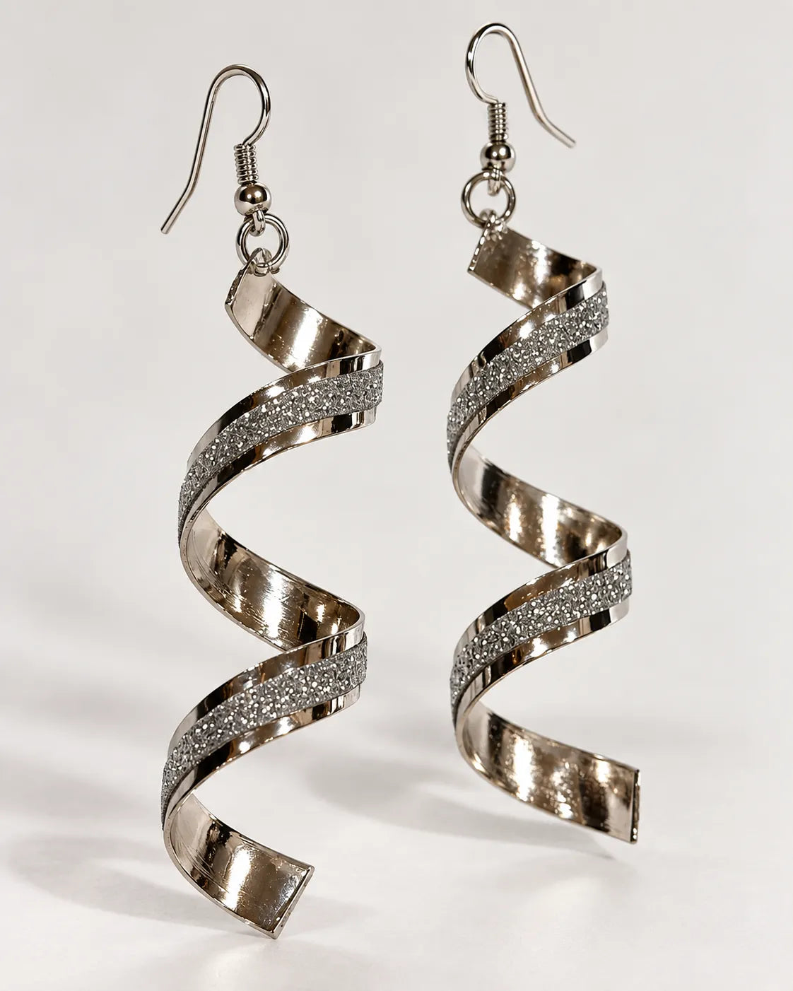 Silver-tone spiral frosted drop earrings hanging on a pale background