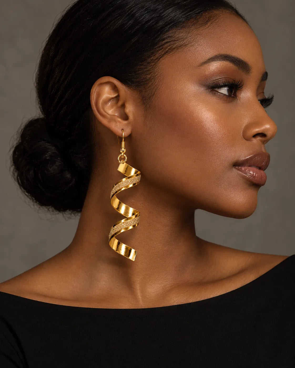 Side profile of a model in a black top wearing the gold spiral earrings