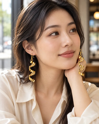 Model in a white shirt at a café wearing the gold spiral drop earrings