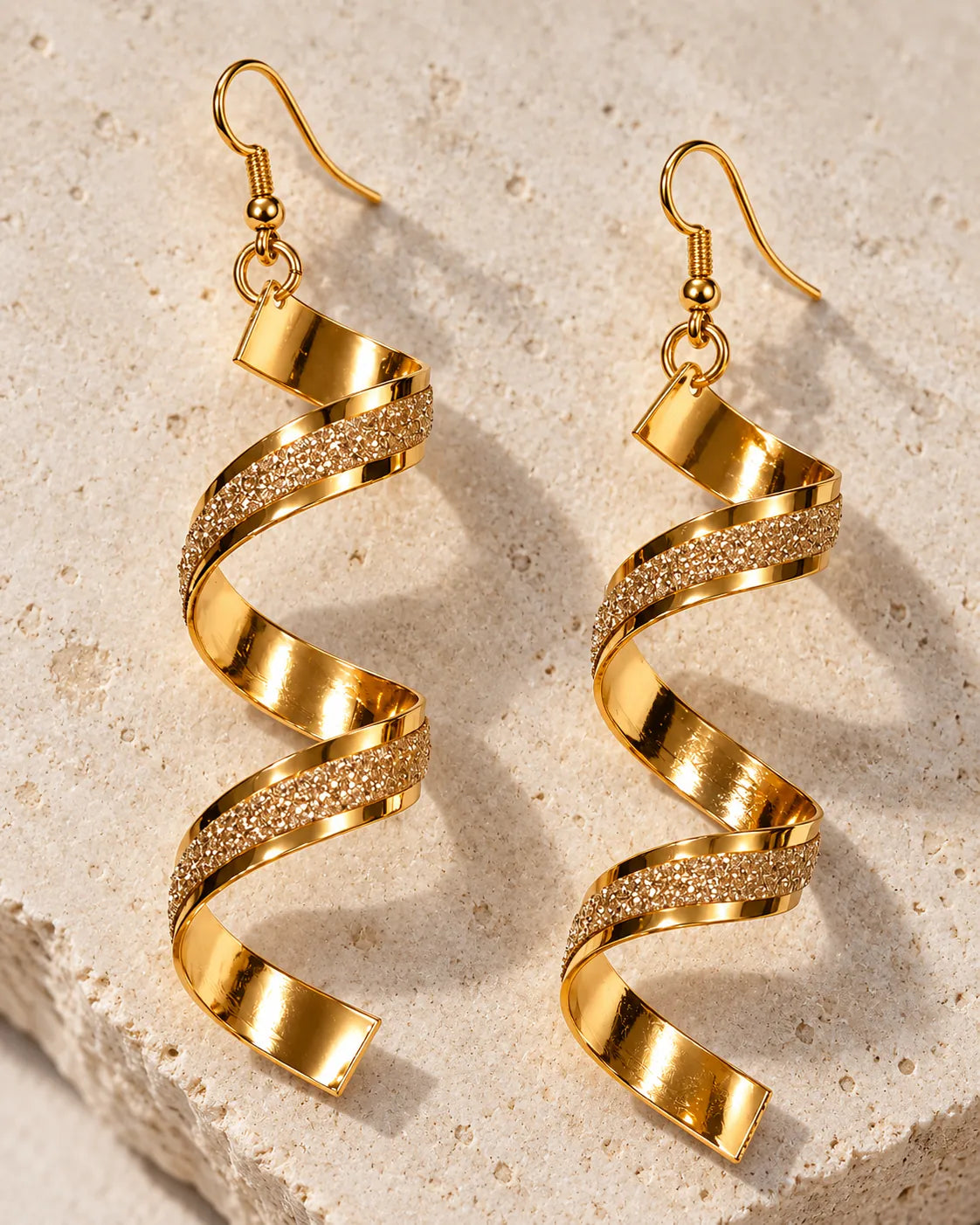 Gold corkscrew spiral earrings resting on a stone block