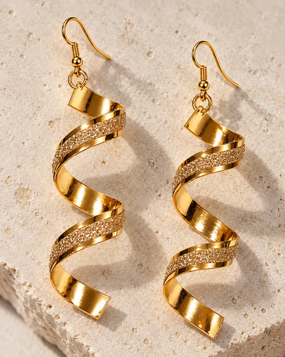 Gold corkscrew spiral earrings resting on a stone block