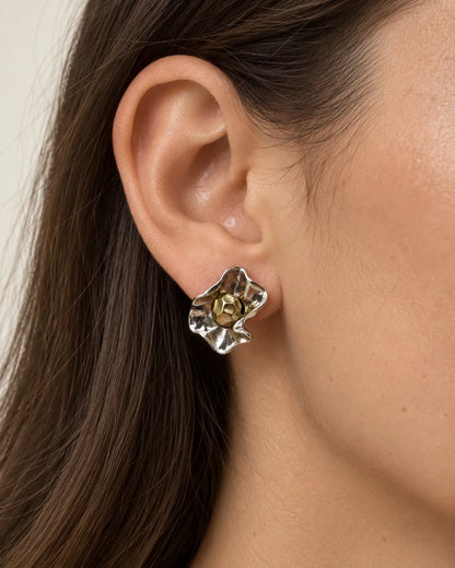 Close-up of a model's ear wearing the two-tone metal flower stud