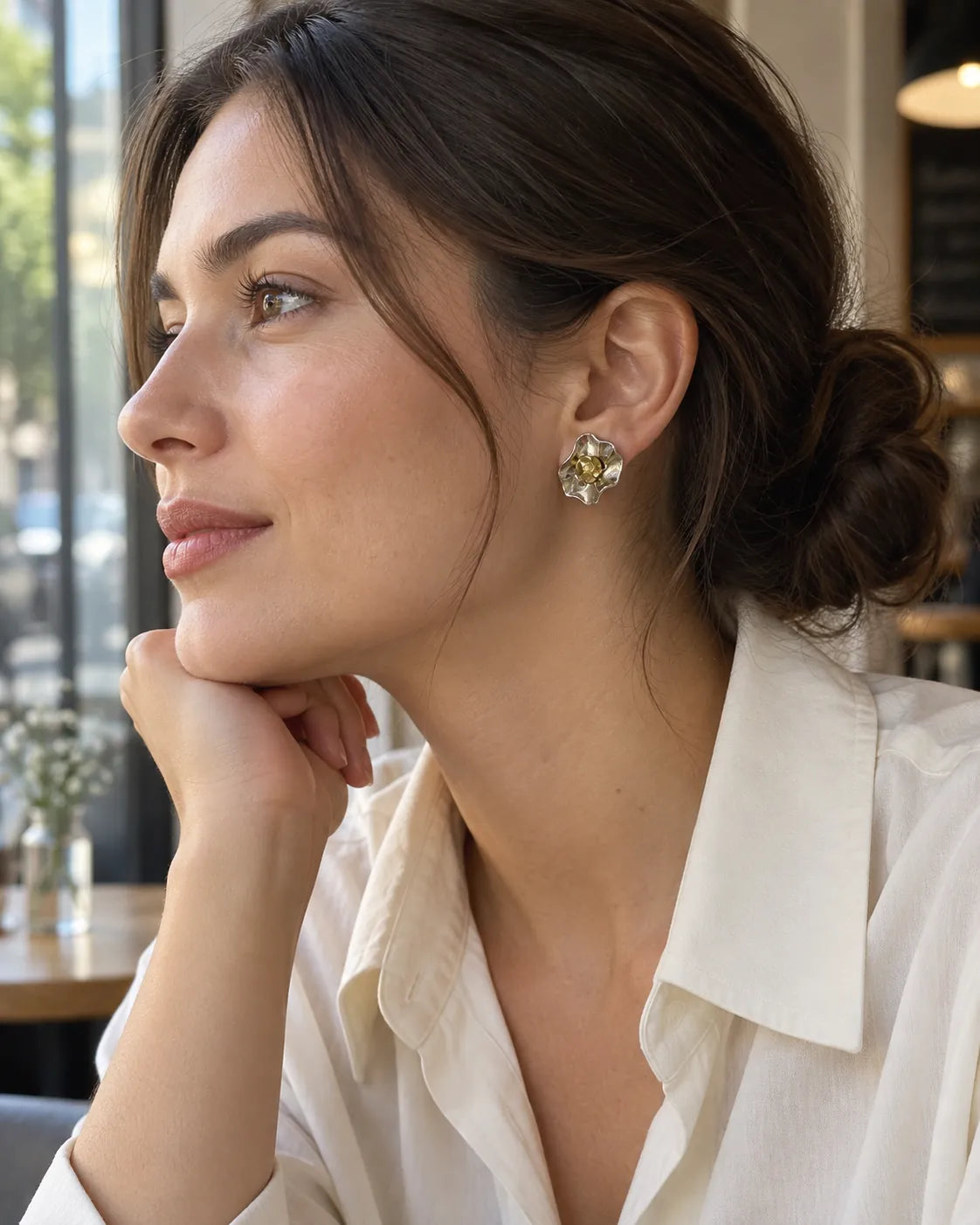 Model in a white shirt at a cafe wearing the sculptural flower studs