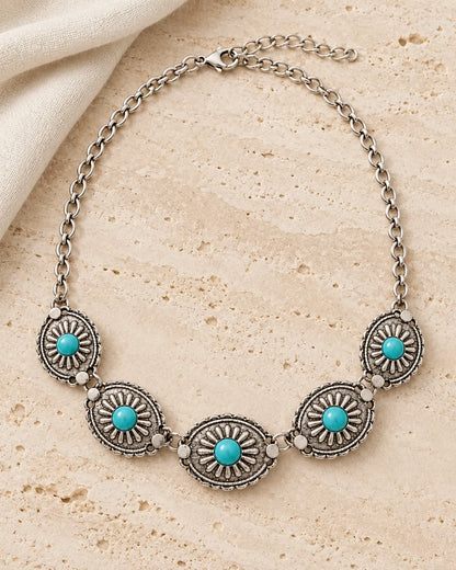 Antique silver-tone turquoise medallion choker on a stone surface