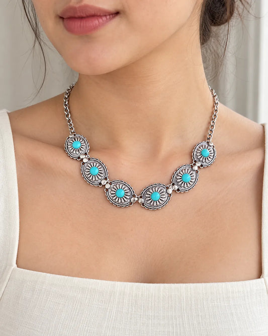 Model in a white square-neck top wearing the turquoise sunburst choker