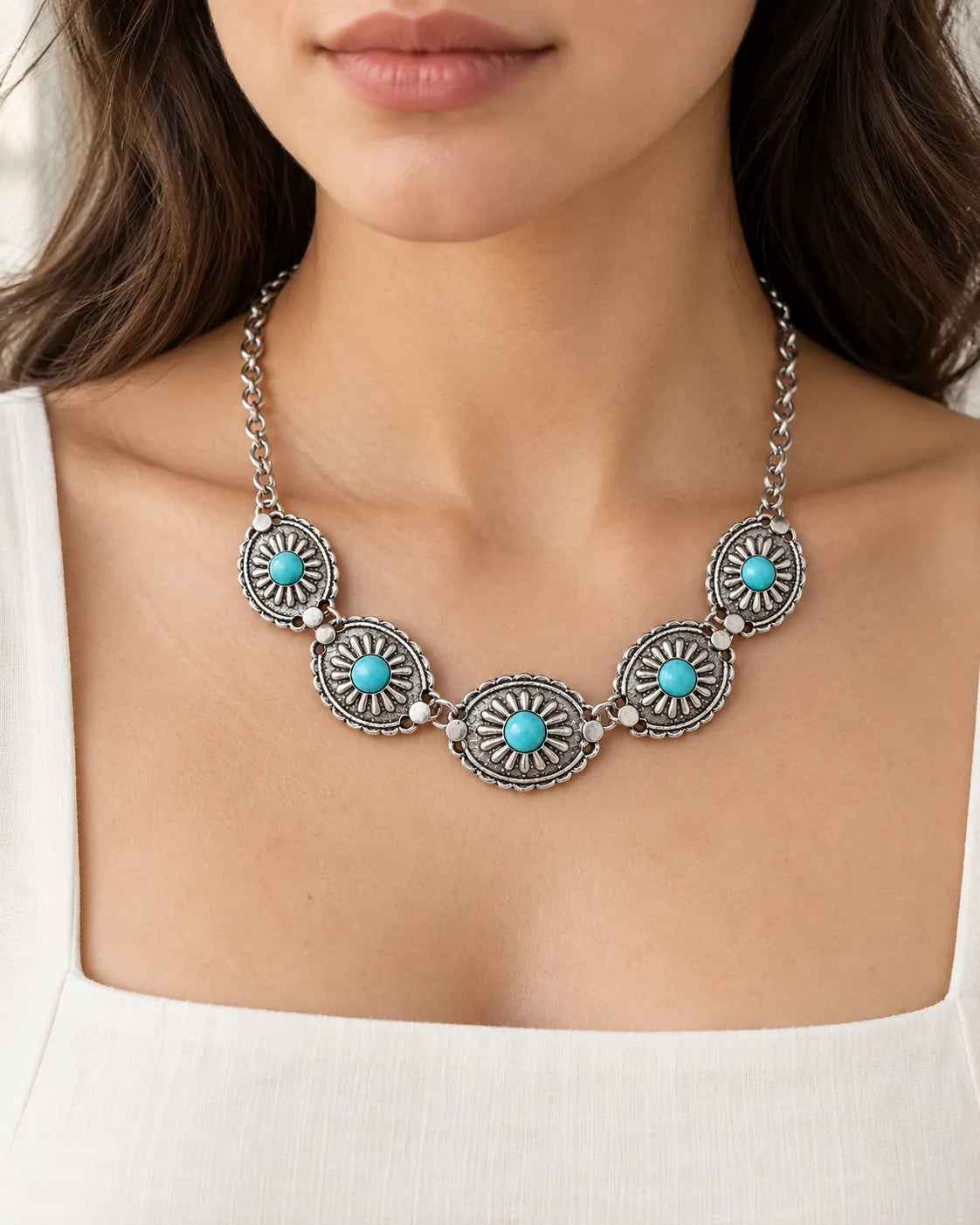 Close-up of the turquoise sunburst choker worn above a white neckline