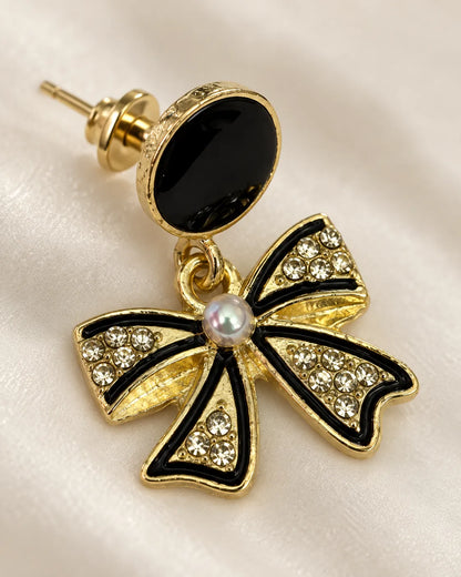 Close-up of one black bow earring showing rhinestone-filled loops and pearl-look knot