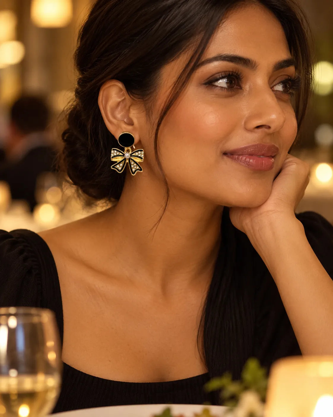 Model at an evening dinner wearing the black bow dangle earrings