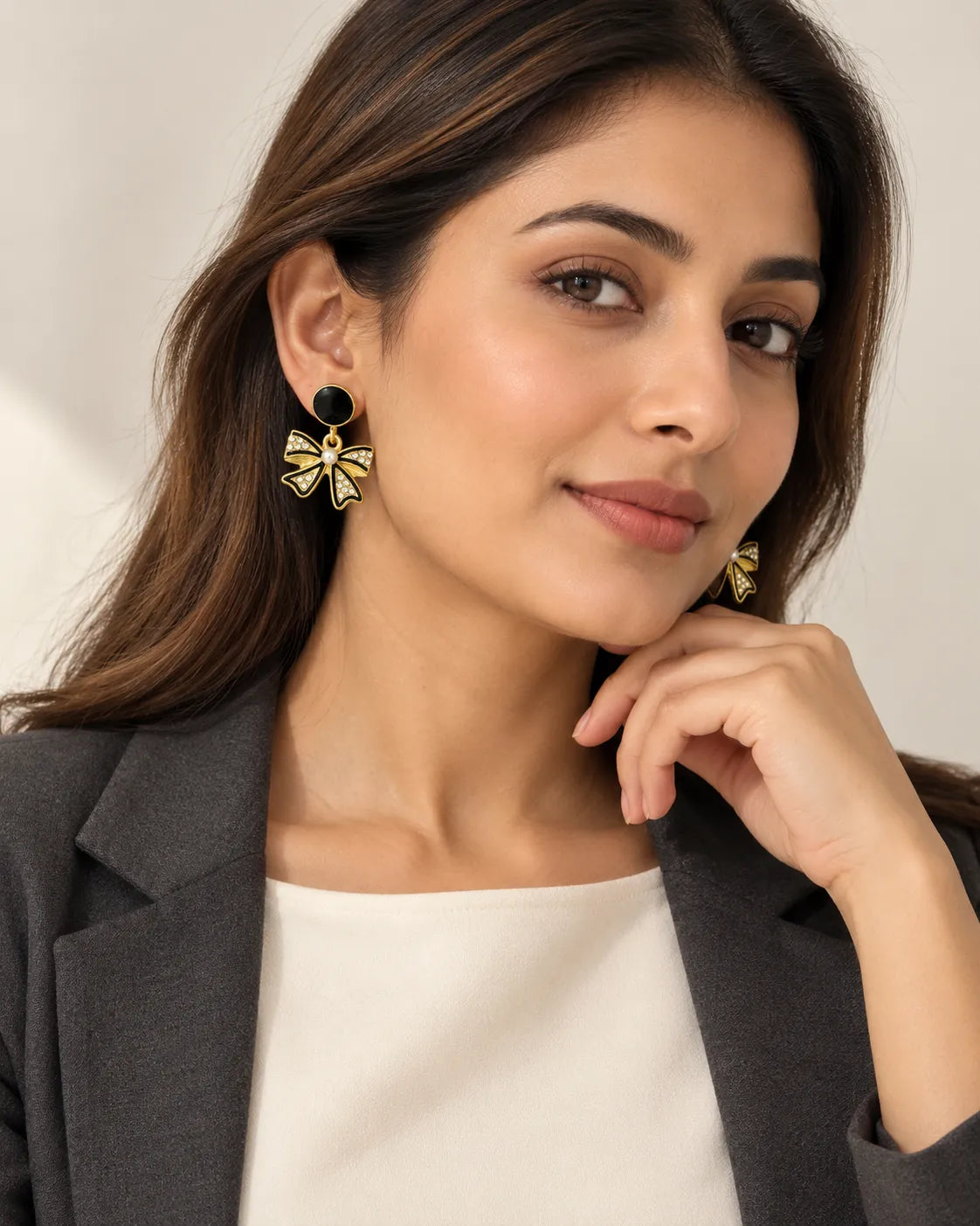 Model in a dark blazer wearing the black bow and pearl-look earrings